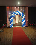 Ballonnenboog in blauw en wit bij een ingang met rode loper
